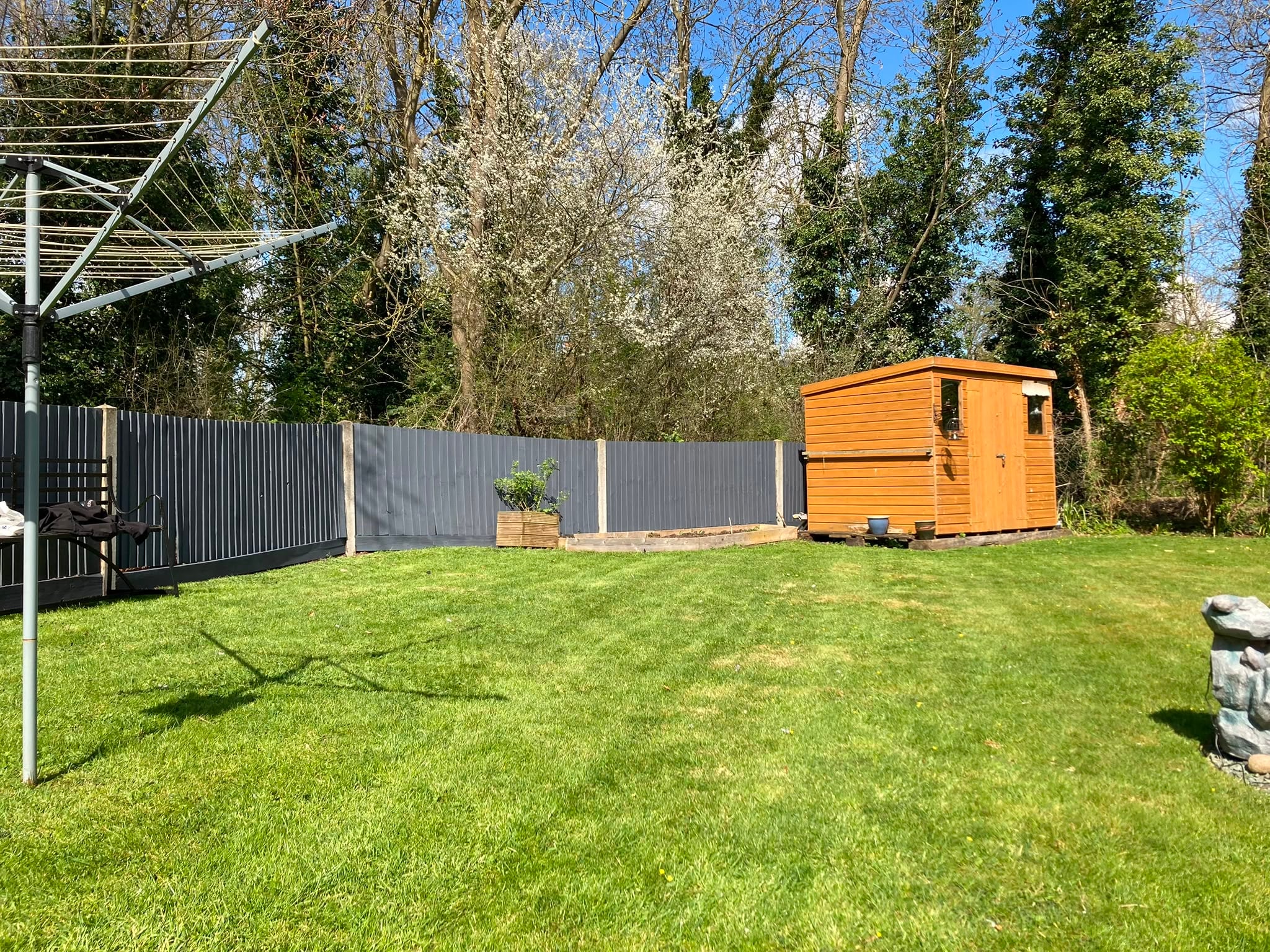 The same boundary re-coated in slate grey, with the shed re-stained a warm honey to match